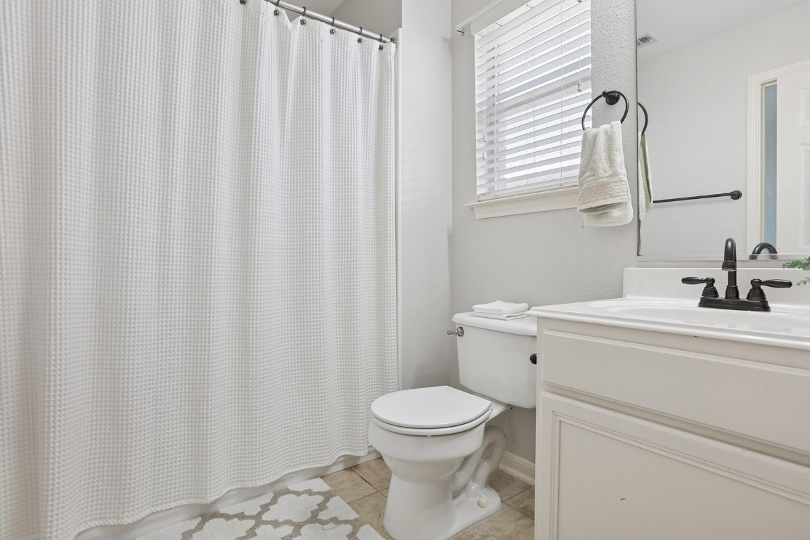 11217 Terrace Meadow Way Manor, TX 78653 - Photo 18 of 33 Bathroom with light tile patterned flooring, vanity, and shower / bath combo with shower curtain