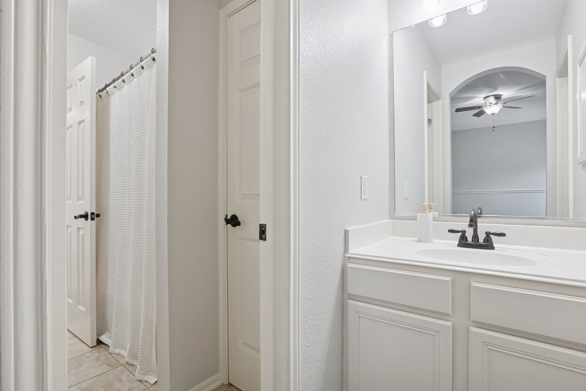 11217 Terrace Meadow Way Manor, TX 78653 - Photo 23 of 33 Full bath with vanity, a shower with curtain, a ceiling fan, and light tile patterned floors