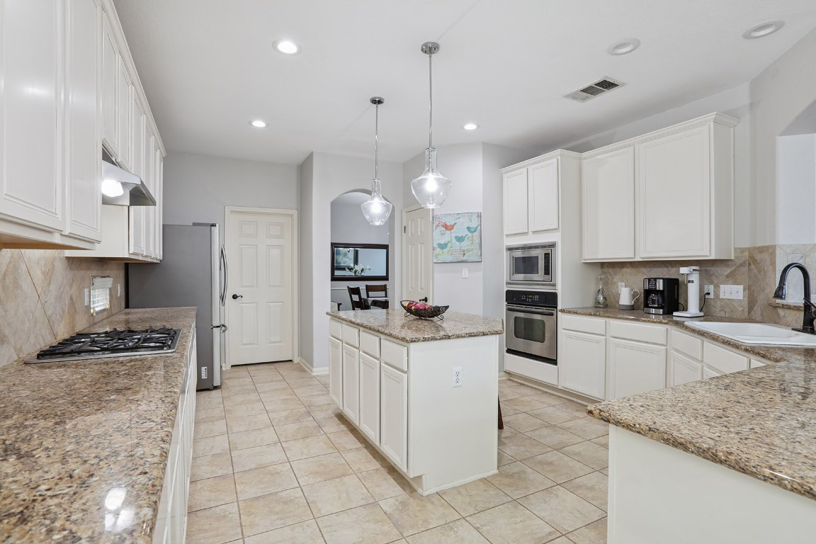 11217 Terrace Meadow Way Manor, TX 78653 - Photo 8 of 33 Kitchen with tasteful backsplash, white cabinetry, hanging light fixtures, appliances with stainless steel finishes, and recessed lighting
