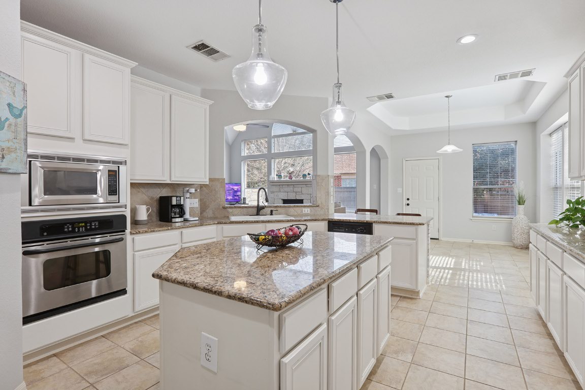 11217 Terrace Meadow Way Manor, TX 78653 - Photo 9 of 33 Kitchen featuring pendant lighting, appliances with stainless steel finishes, light tile patterned flooring, a peninsula, and a kitchen island
