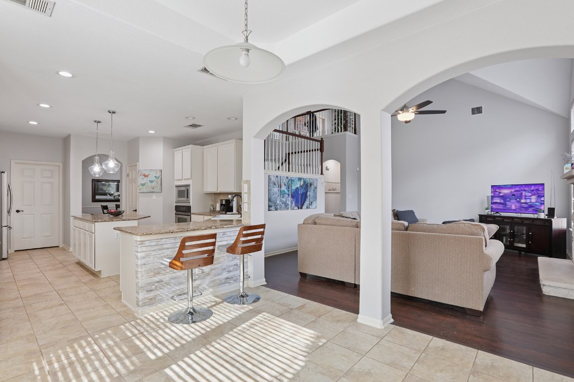 11217 Terrace Meadow Way Manor, TX 78653 - Photo 10 of 33 Kitchen with light tile patterned floors, white cabinets, pendant lighting, ceiling fan, and light stone counters