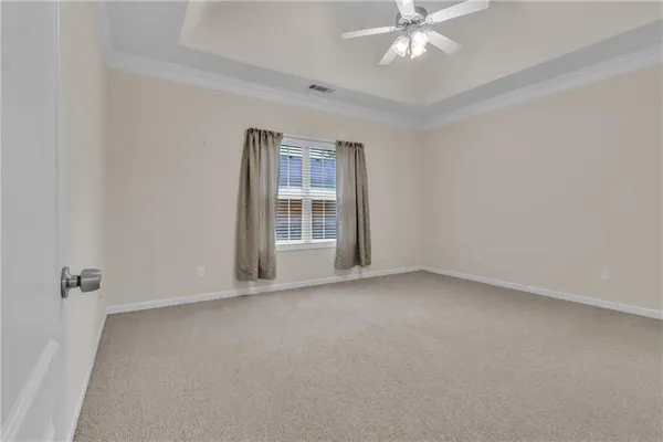 an empty room with chandelier fan and windows
