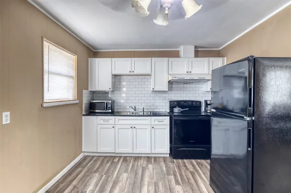 a kitchen with granite countertop a refrigerator sink and cabinets