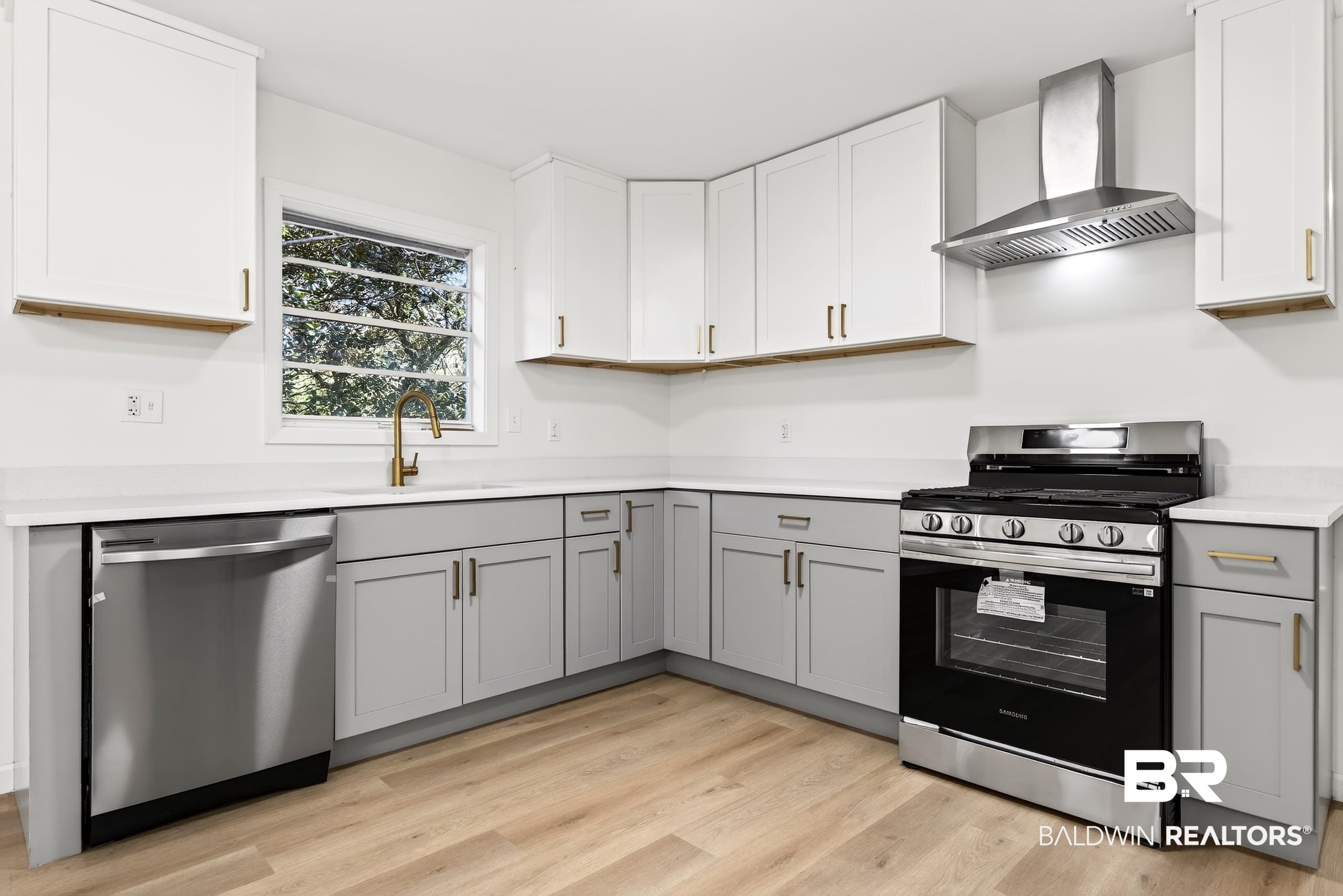 30902 Stanton Road Spanish Fort, AL 36527 - Photo 5 of 27 Kitchen with appliances with stainless steel finishes, wall chimney exhaust hood, gray cabinets, light wood-style floors, and white cabinets