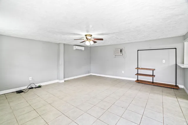 an empty room with windows and ceiling fan