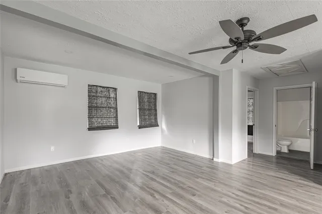 a view of an empty room with wooden floor and a ceiling fan