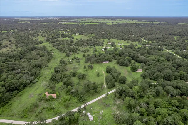 an aerial view of residential houses with outdoor space and trees