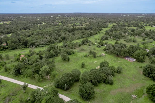 an aerial view of residential houses with outdoor space and trees