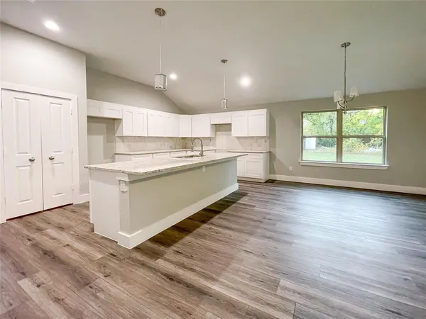 a kitchen with stainless steel appliances granite countertop a stove a sink and white cabinets with wooden floor