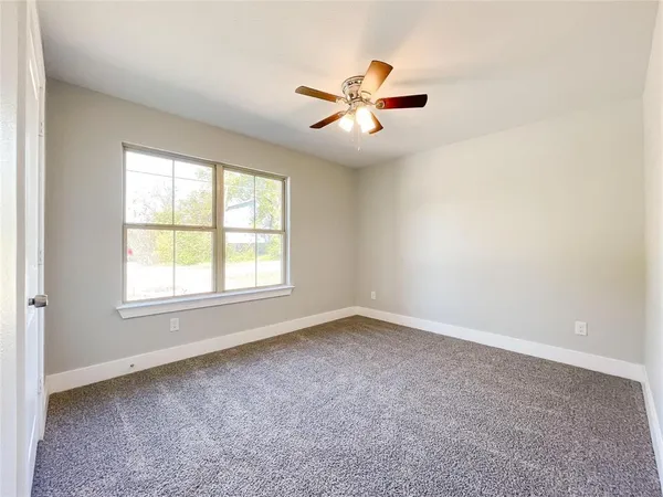 an empty room with a window and a fan
