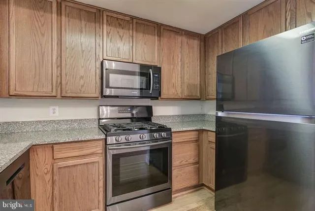 a kitchen with granite countertop cabinets stainless steel appliances and a counter space