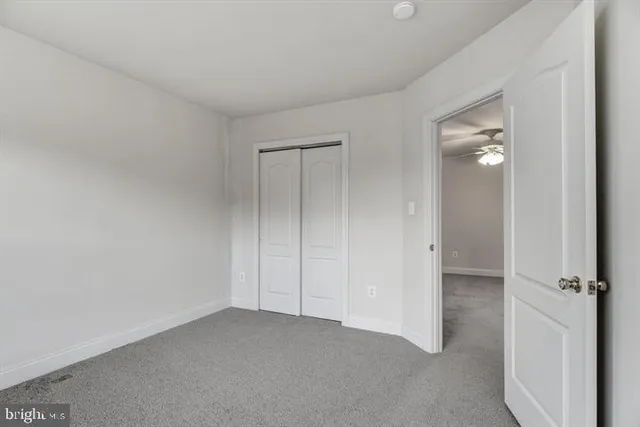 a view of an empty room with closet and mirror