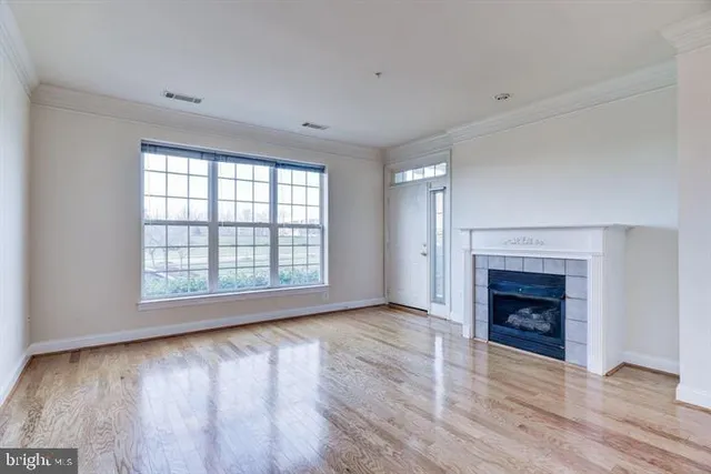 an empty room with wooden floor fireplace and windows