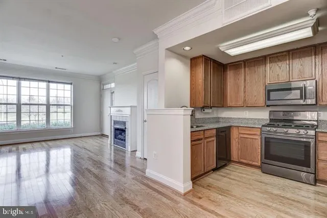 a kitchen with stainless steel appliances granite countertop a stove top oven a sink dishwasher and a refrigerator with wooden floor