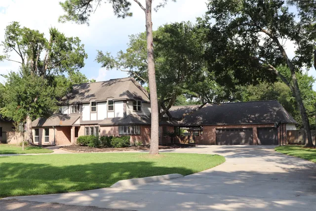 a view of a white house next to a yard with big trees