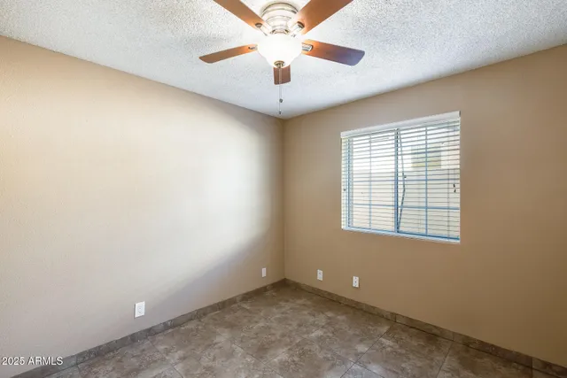 an empty room with a window and a ceiling fan