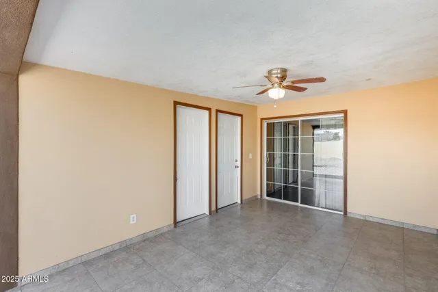an empty room with windows and ceiling fan