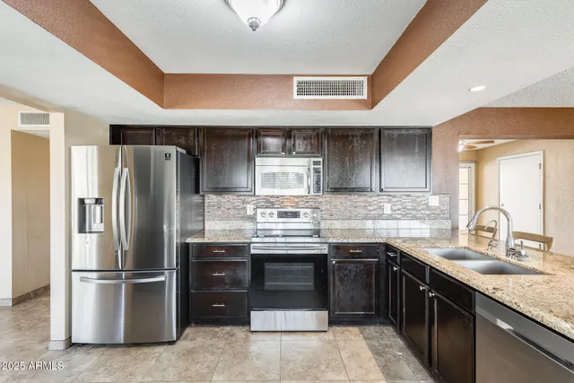 a kitchen with stainless steel appliances granite countertop a sink stove and refrigerator