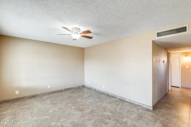 an empty room with a chandelier fan and windows