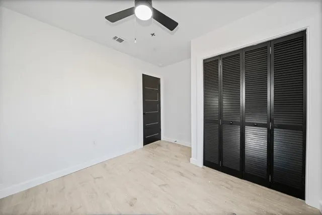 an empty room with a window and ceiling fan