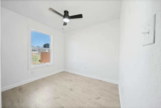 an empty room with a window and a fan