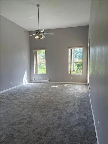 an empty room with windows and ceiling fan