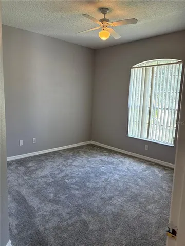 an empty room with windows and ceiling fan