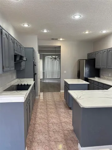 a large kitchen with stainless steel appliances a large counter top a stove a sink a refrigerator and a oven