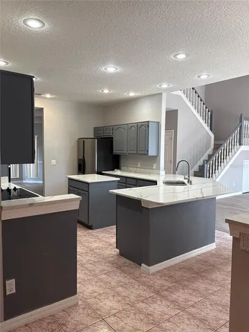 a large kitchen with kitchen island a sink a counter top space appliances and cabinets