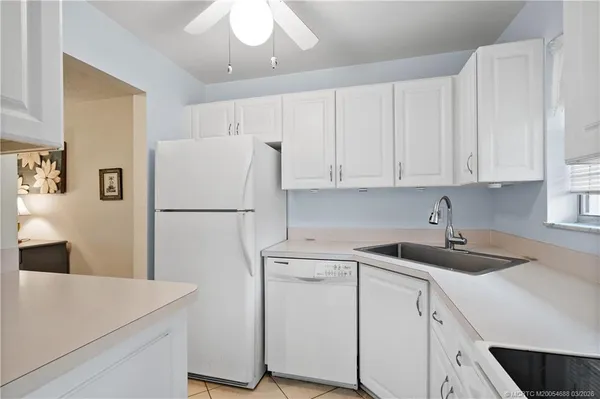 a kitchen with a sink a refrigerator and white cabinets