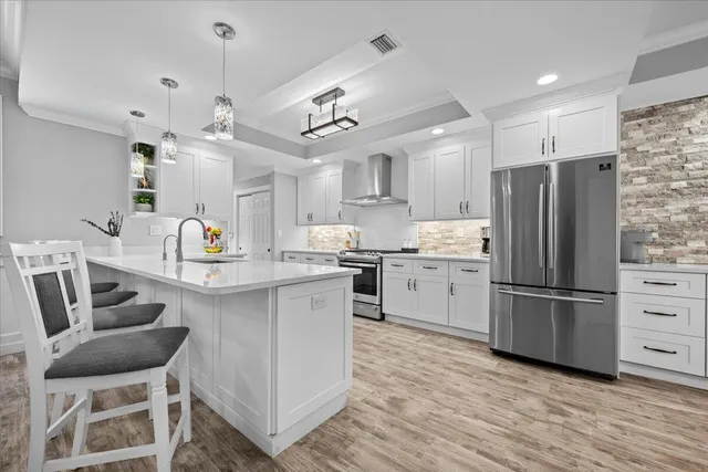 a large white kitchen with a lot of counter space and a chandelier