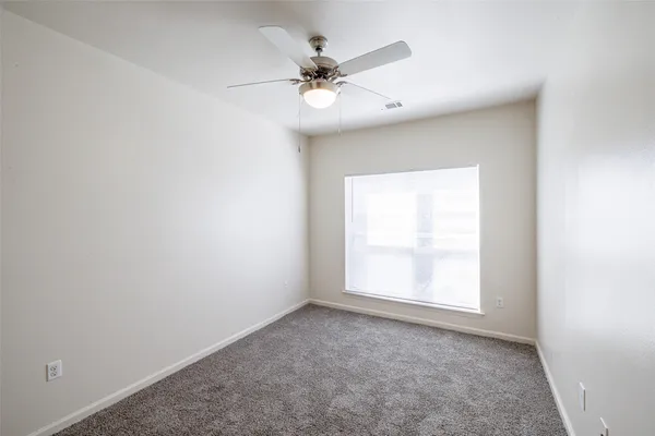 an empty room with a window and a ceiling fan