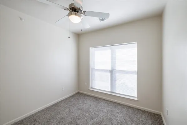 an empty room with a window and a fan