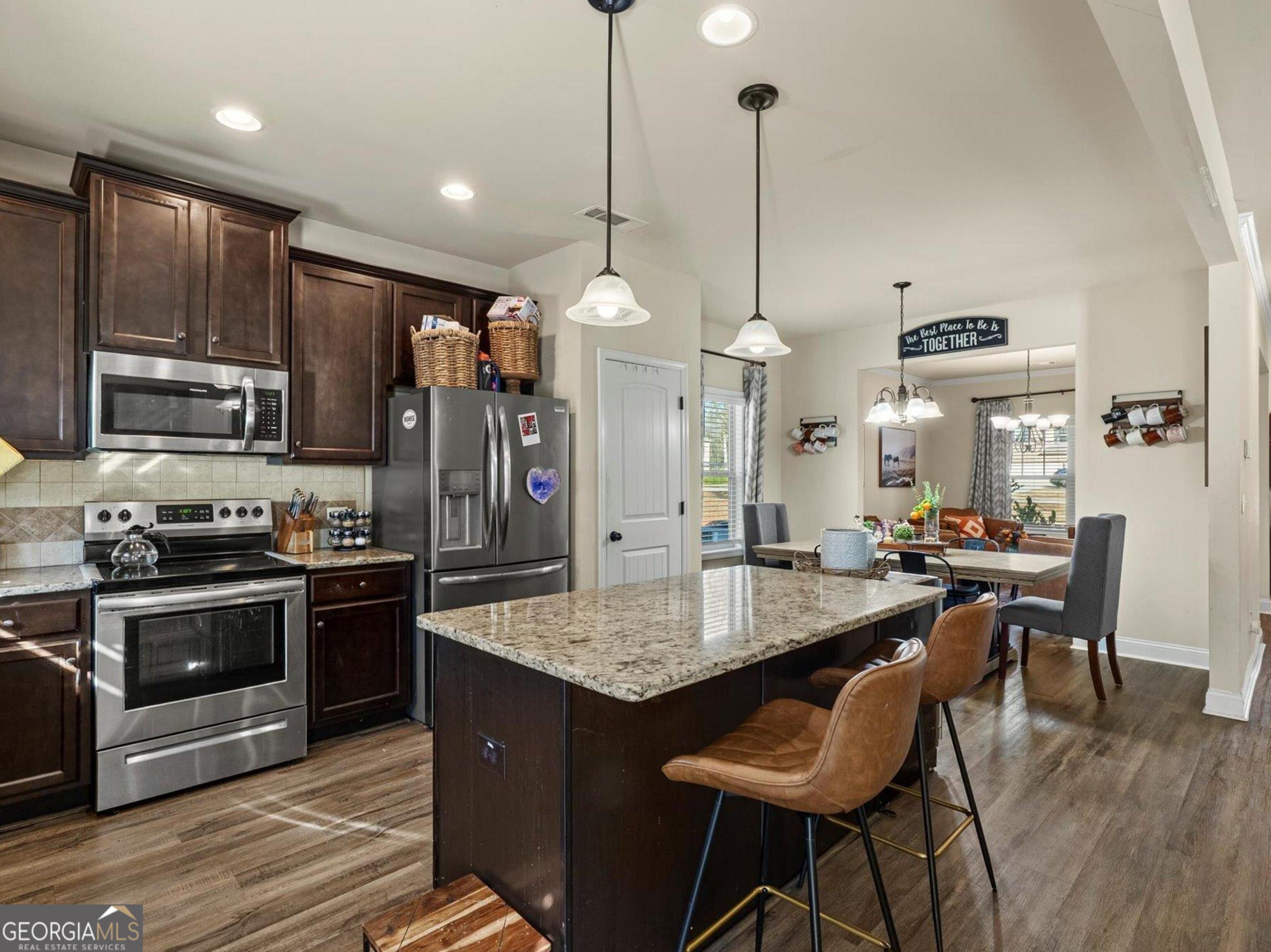 976 Jackson Street Locust Grove, GA 30248 - Photo 7 of 17 a kitchen with stainless steel appliances granite countertop a stove a kitchen island a dining table and chairs