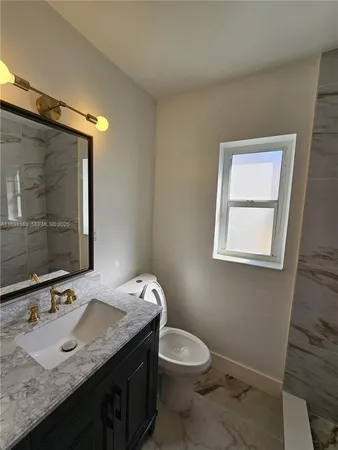 a bathroom with a granite countertop toilet a sink and a mirror