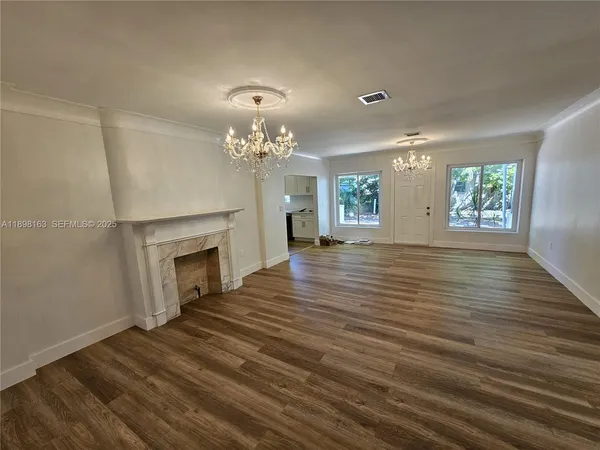 a view of a livingroom with a fireplace wooden floor and chandelier