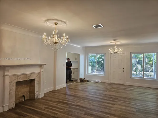 a view of a room with wooden floor fireplace and windows