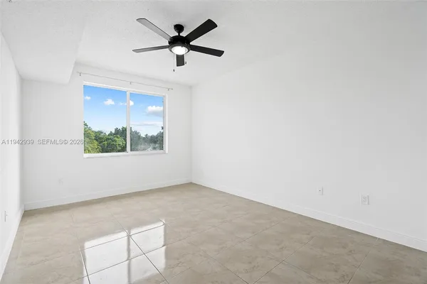 an empty room with a window and a ceiling fan