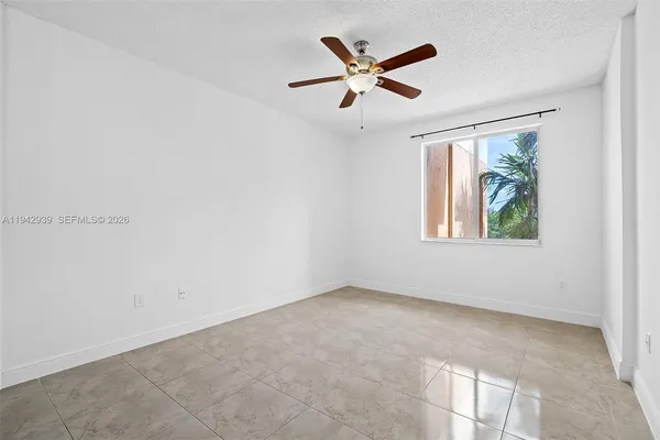 an empty room with windows and ceiling fan