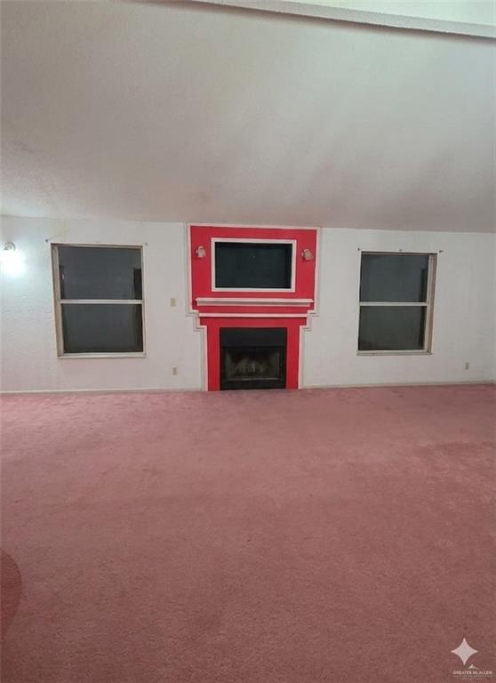 4347 Highway 83 Rio Grande City, TX 78582 - Photo 6 of 15 Spacious room featuring a central fireplace with a bold red surround and mantel, two windows, and wall-to-wall carpeting