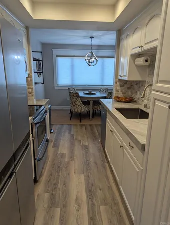 a kitchen with granite countertop a sink a counter space stainless steel appliances and cabinets