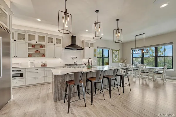 a kitchen with stainless steel appliances a dining table chairs stove and wooden floor