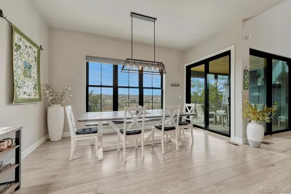 a dining room with wooden floor a chandelier a glass table and chairs