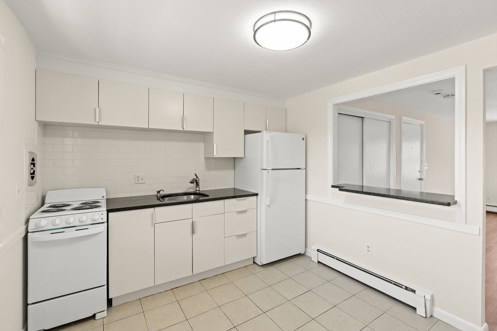 2 Colonial Drive, Unit E25 Andover, MA 01810 - Photo 9 of 17 a kitchen with a sink a stove a refrigerator and white cabinets