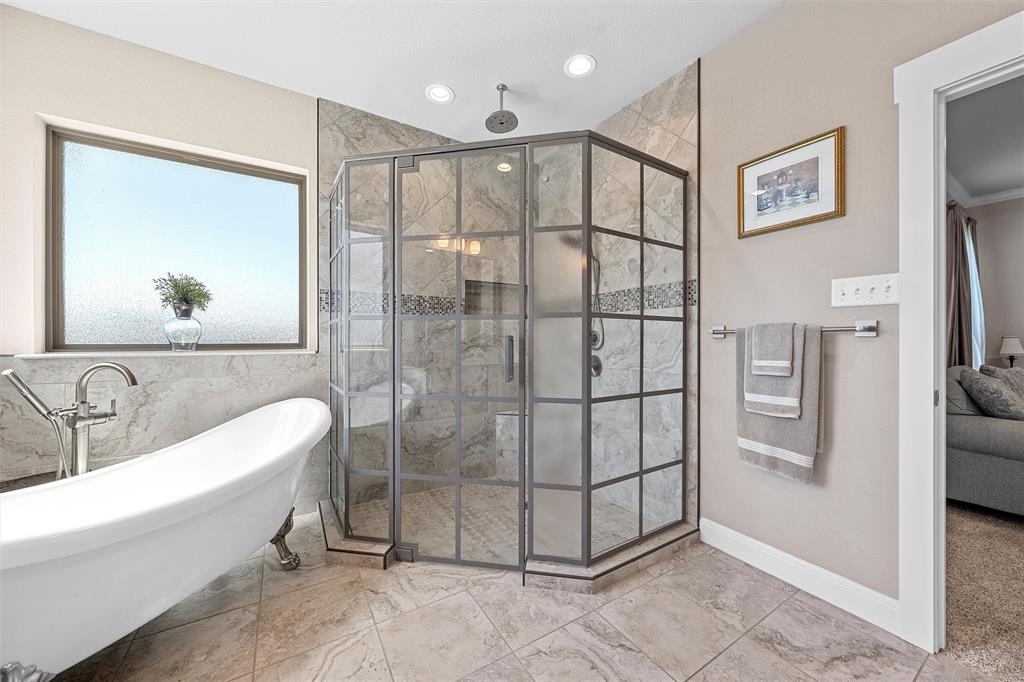 23 Independence Trail Waco, TX 76708 - Photo 20 of 35 Bathroom featuring a freestanding clawfoot tub with a deck-mounted faucet, a corner glass-enclosed shower with a rain showerhead, and light-toned tile flooring