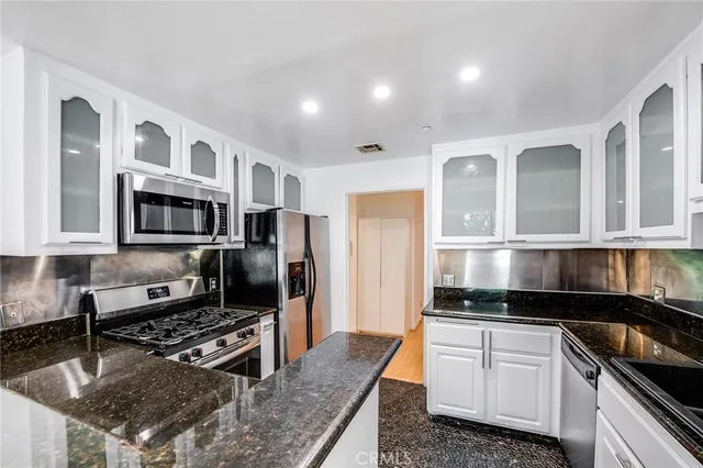 a kitchen with granite countertop a sink stove and cabinets