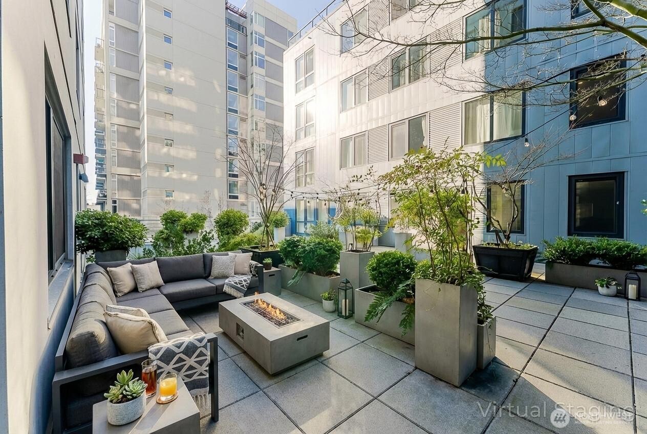 76 Cedar Street, Unit 303 Seattle, WA 98121 - Photo 4 of 29 a view of a patio with couches and a potted plant on a brick wall