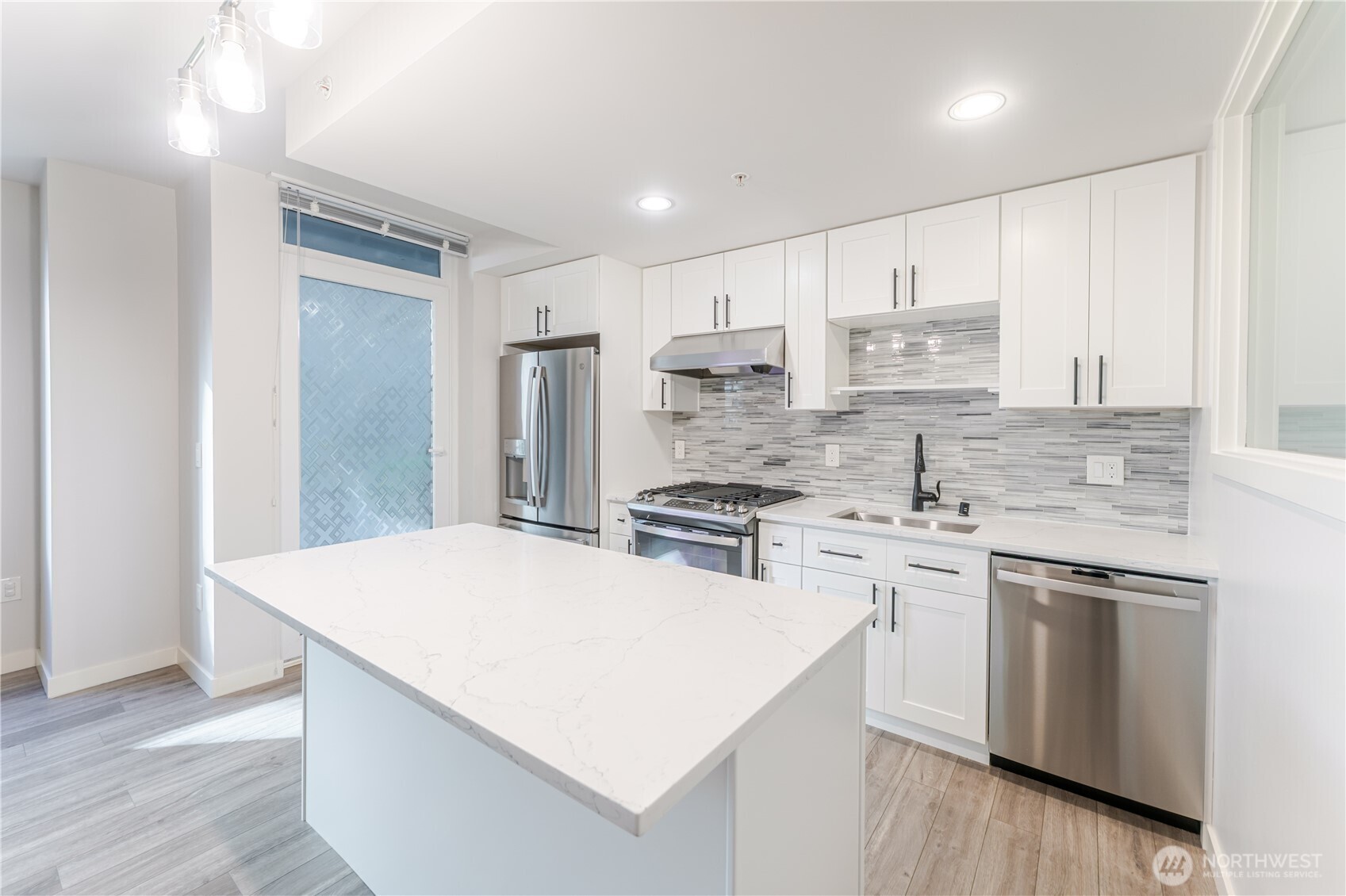 76 Cedar Street, Unit 303 Seattle, WA 98121 - Photo 9 of 29 a kitchen with stainless steel appliances a white stove top oven sink and cabinets