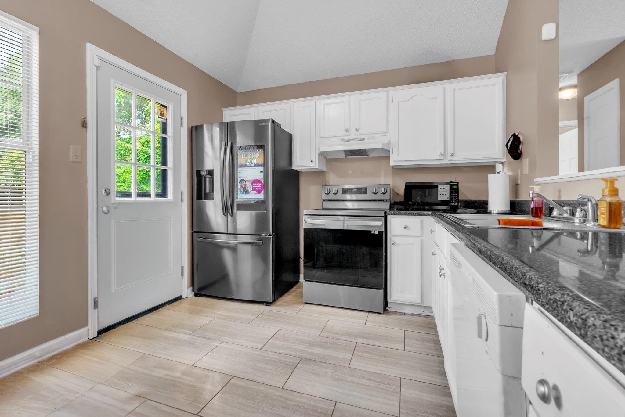 5930 Chadwell Road Millington, TN 38053 - Photo 10 of 17 Kitchen featuring stainless steel appliances, wood-finish tile flooring, white cabinetry, dark speckled countertops, and a full-light exterior door