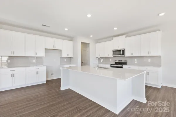 a kitchen with stainless steel appliances a refrigerator sink and white cabinets